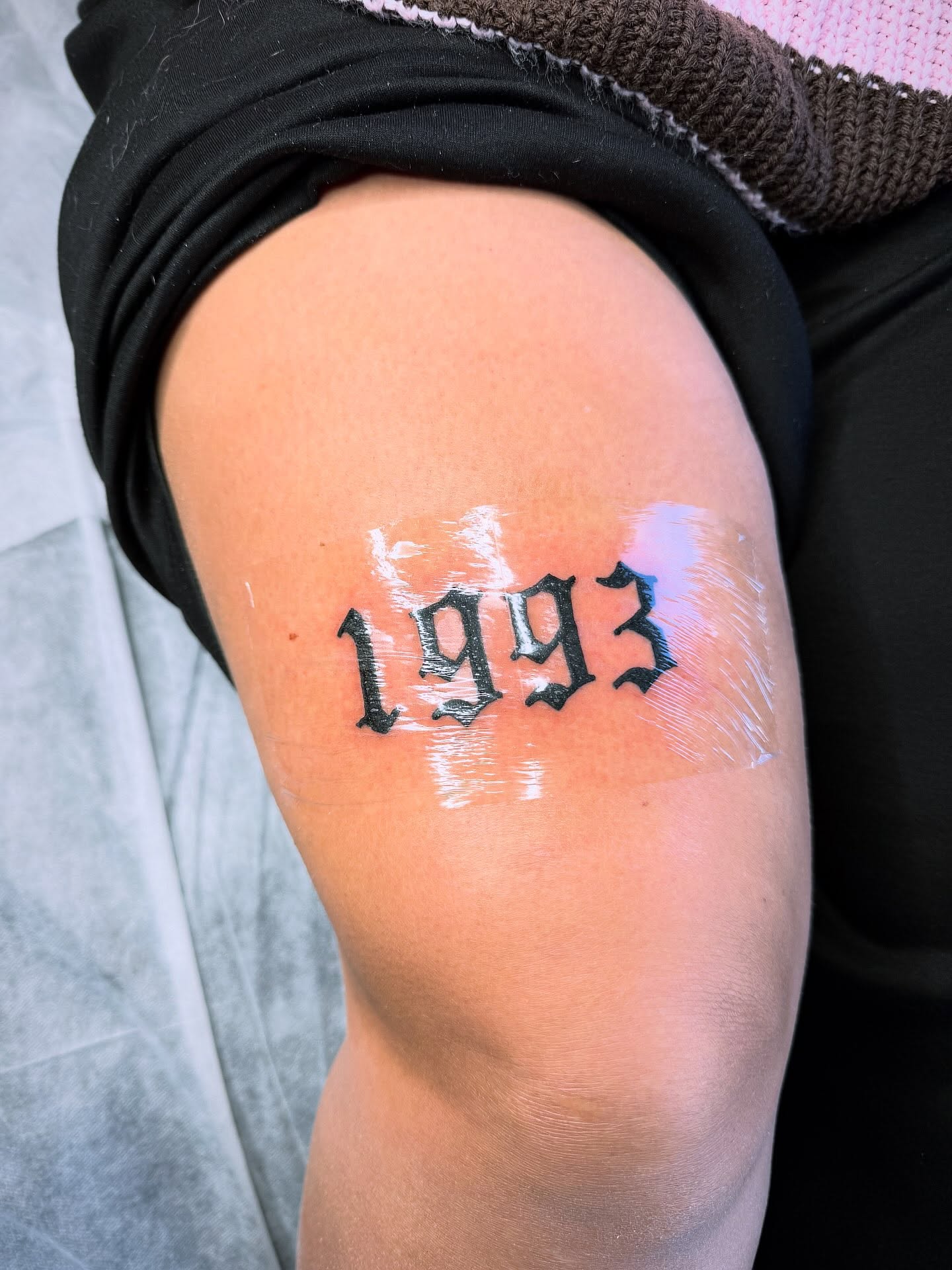 The numerals 1993 tattooed in bold blackletter script on an arm