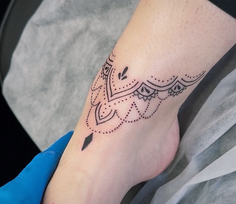 An ornamental dotwork band tattooed around an ankle